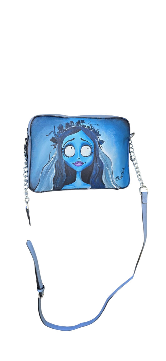 *✨ Il Soggetto: La Sposa Cadavere (Emily)*
Porta con te la poesia del capolavoro di Tim Burton con questa borsa in ecopelle, dipinta interamente a mano. La protagonista Emily, con la sua corona di fiori appassiti e il suo velo etereo, è riprodotta con cura estrema nei dettagli per chi ama lo stile dark-chic e gli accessori che raccontano una storia d'amore eterno.